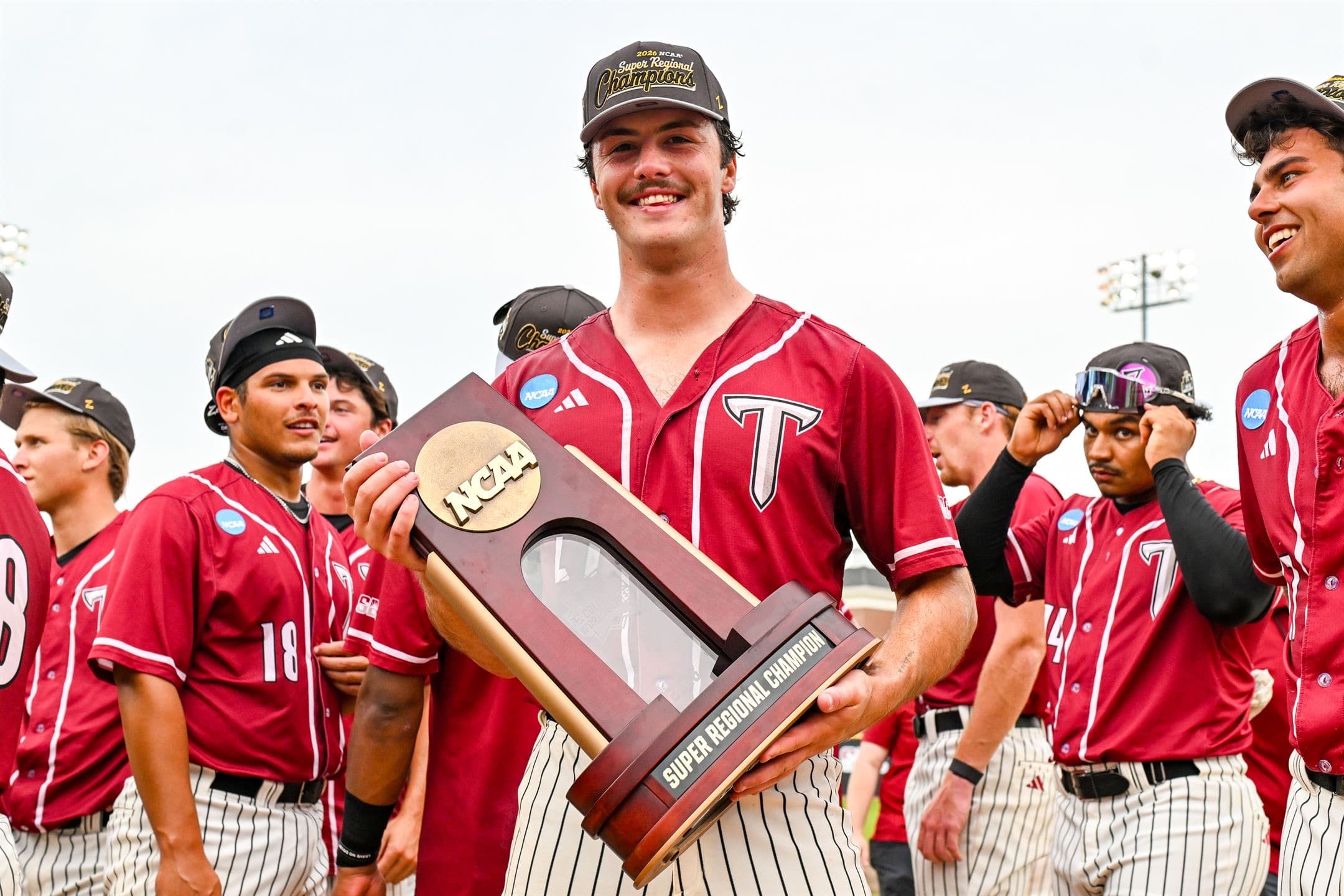 Dylan Alonso holding the NCAA Super Regional Champion trophy with his team