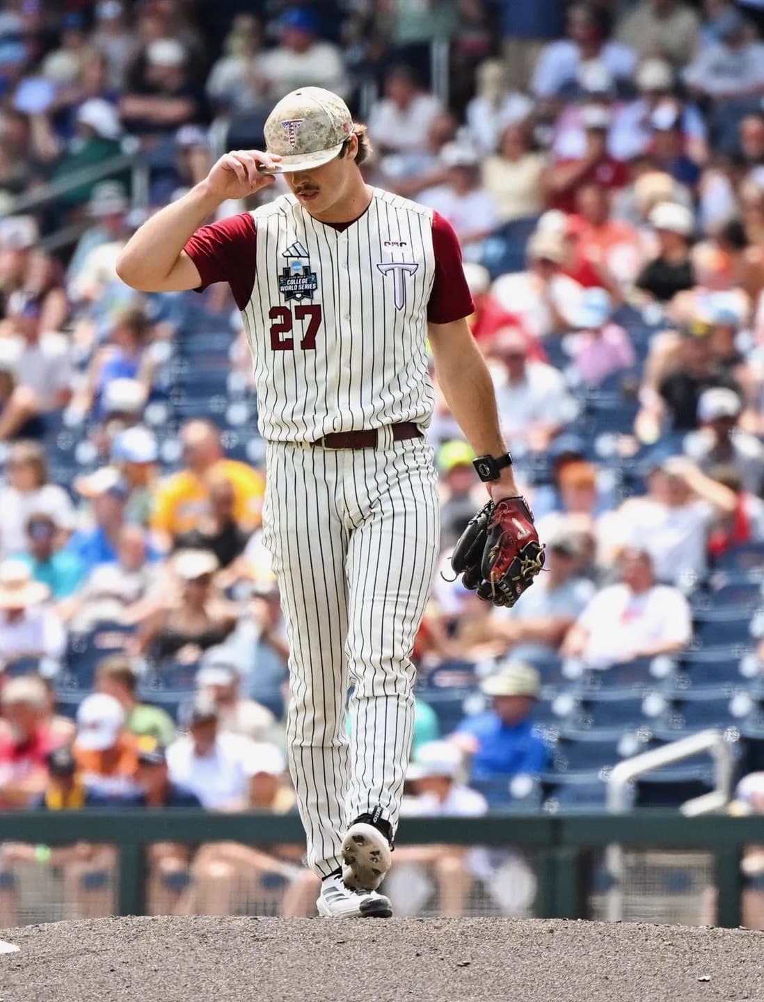 Dylan Alonso tips his cap walking off the College World Series mound